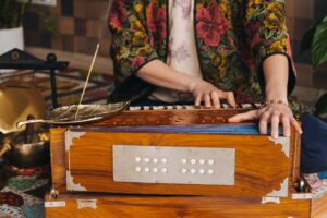Hands of a woman sitting on the floor and playing the harmonium during the practice of kundalini
